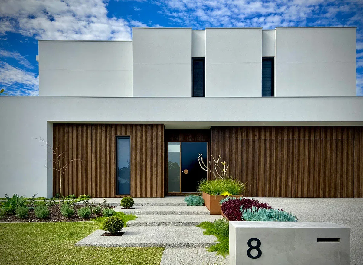 Modern white rendered Penrith home entrance with structural garden bed planting and concrete steps at dusk
